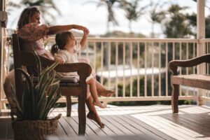 Haus kaufen - Frau sitzt mit Kind auf der Veranda von ihrem Haus, ihrer Wohnung. Immobilienmakler Igel Immobilien.